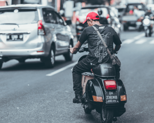Man on a motorcycle merges into traffic on a busy street