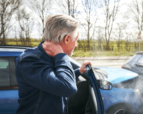Man getting out of car holding his neck