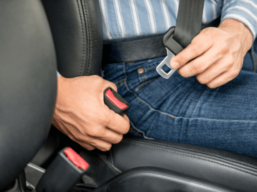 A man putting his seatbelt on.