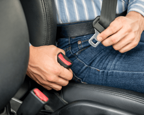 A man putting his seatbelt on.