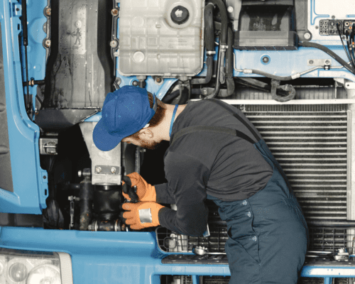 A man working under the hood of a semi truck.